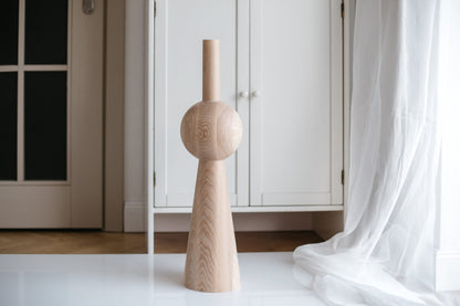 A single wooden furniture leg with a sphere on top stands against a white background, representing a piece of DIY furniture hardware.
